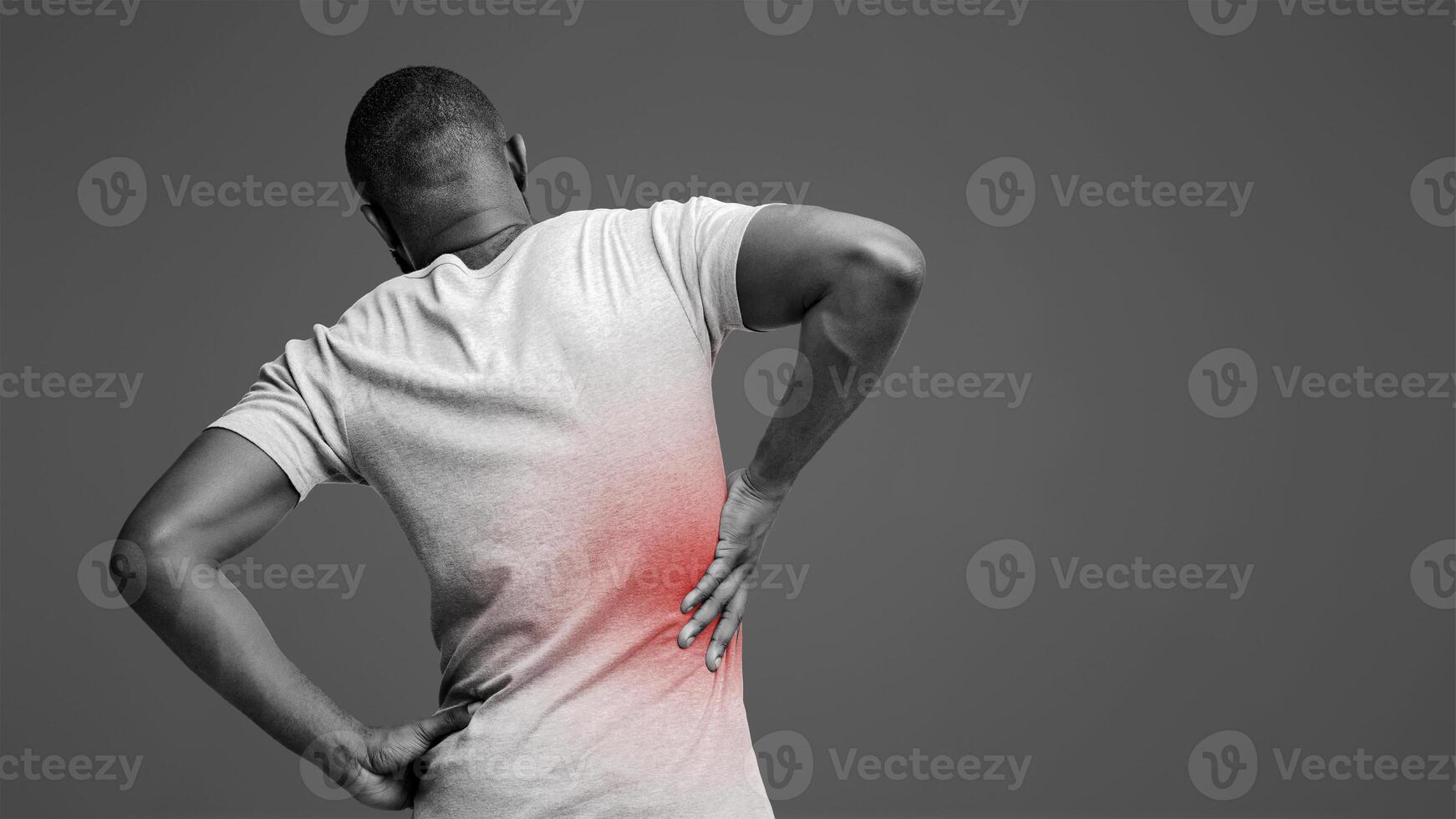 Kidney stones. Afro man holding his hand behind his back, pain in kidney, inflamed zone highlighted in red, back view photo
