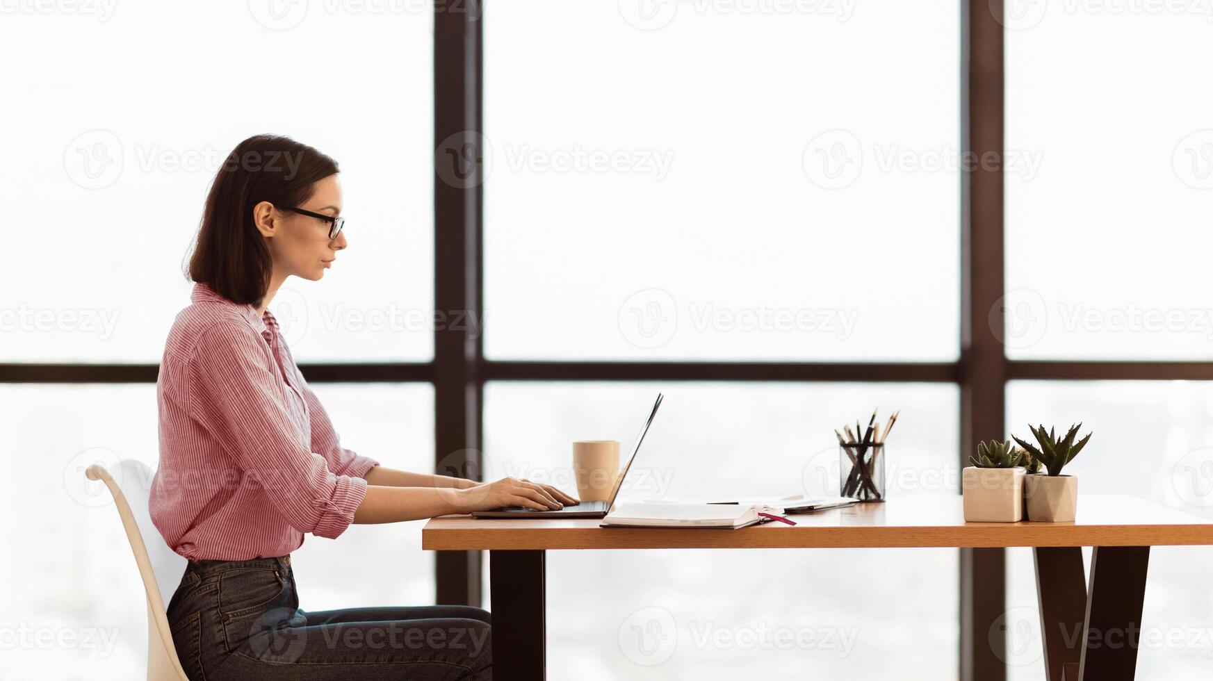 Searching Job. Focused young female worker using laptop, typing on keyboard, looking for business projects, panorama photo