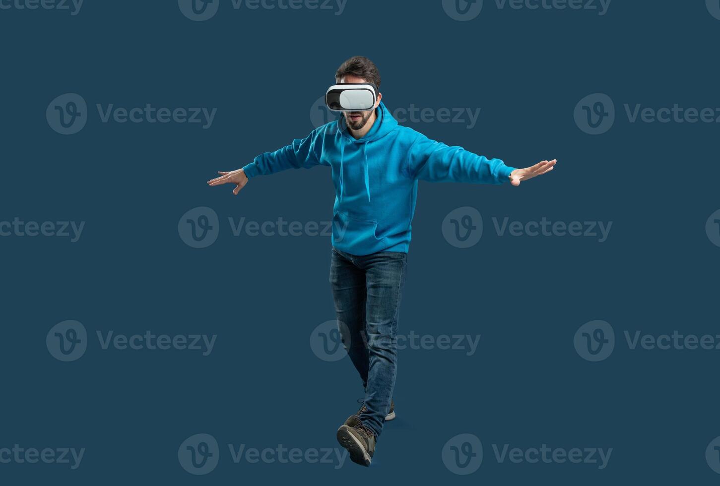 A person wearing a virtual reality headset balances on one foot, immersed in an engaging digital experience. The indoor setting highlights their focus and enthusiasm for technology. photo
