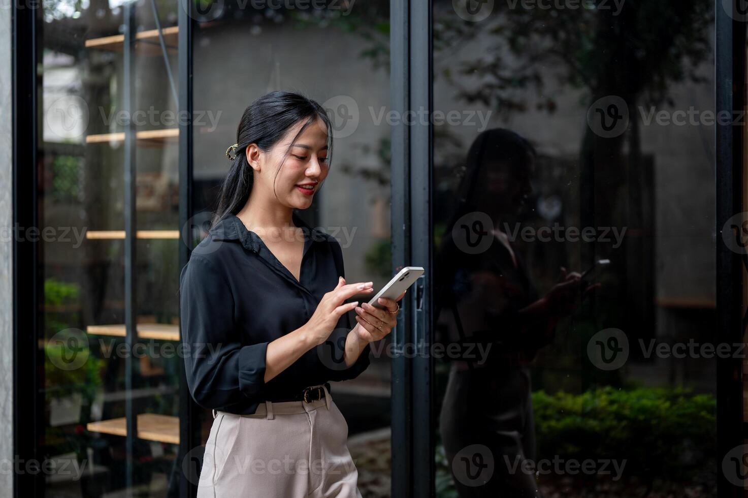 A confident businesswoman is replying to chats on her phone while walking through an office corridor photo