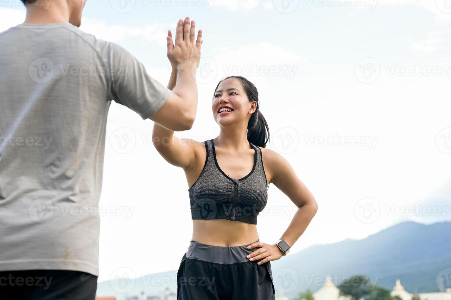An active, happy Asian couple in sportswear gives each other a high five after running together. photo
