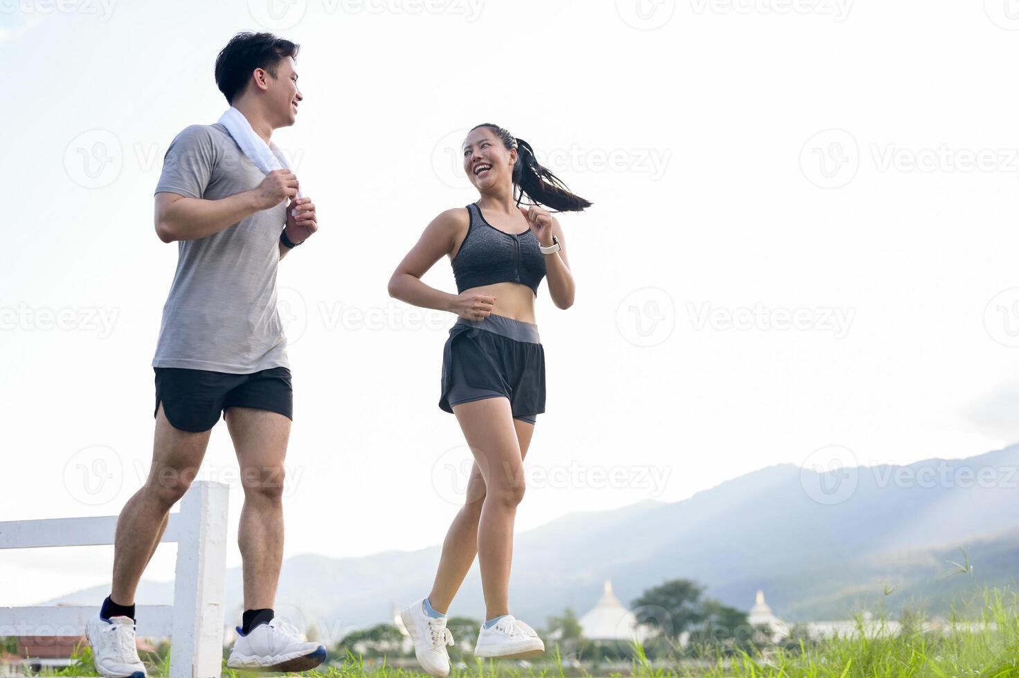 A sporty, active Asian couple in sportswear is enjoying a run or jog together at a park by the lake. photo