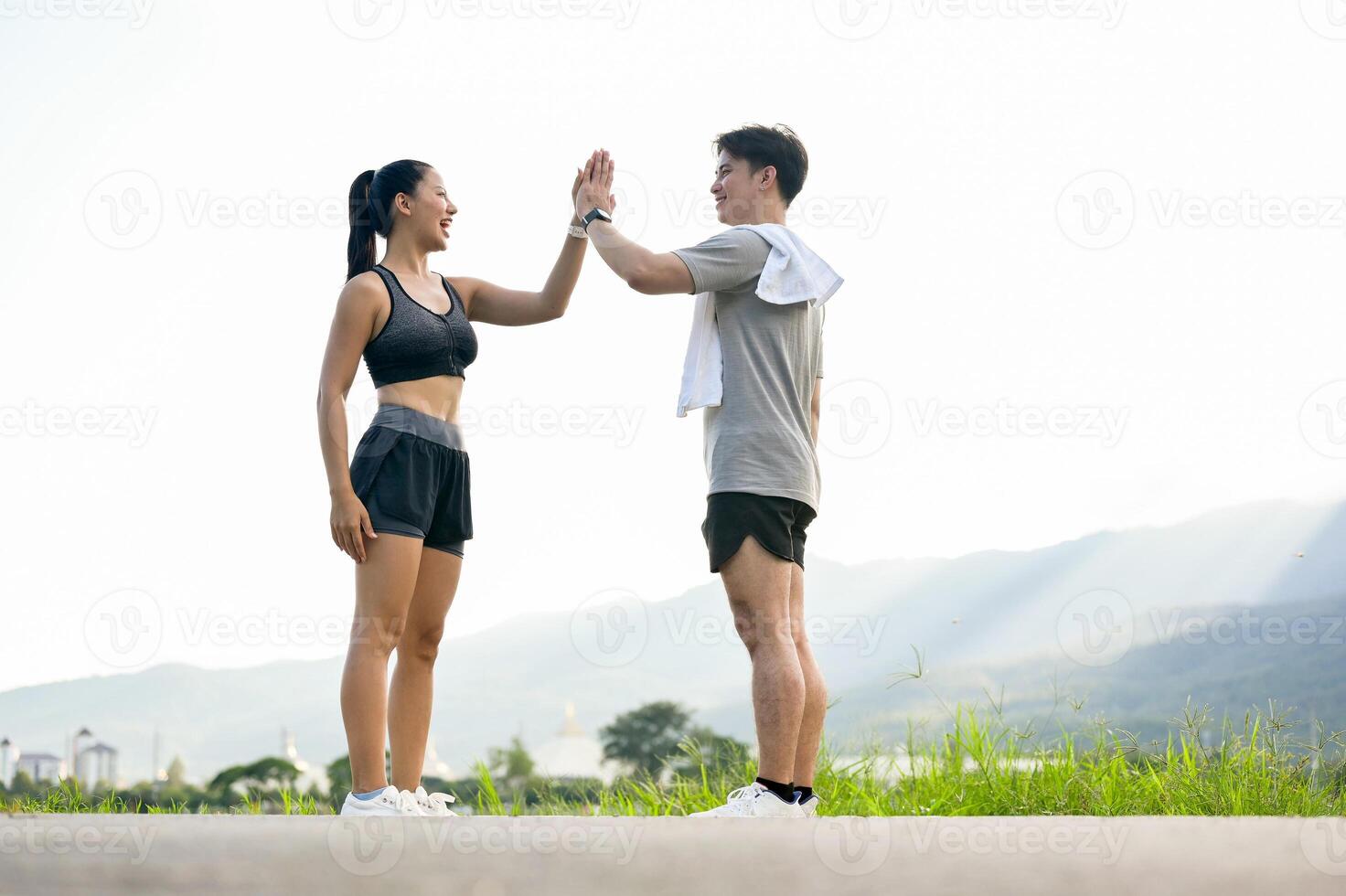 An active, happy Asian couple in sportswear gives each other a high five after running together. photo