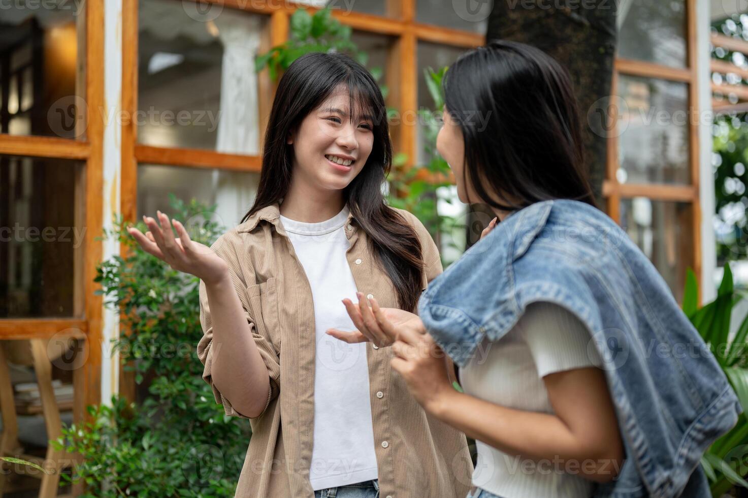 Two cheerful Asian female friends are enjoying a conversation while walking through a garden. photo