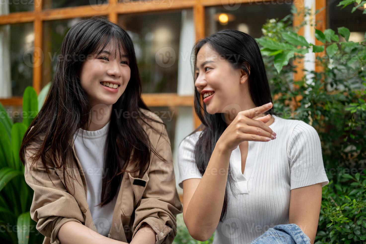 Two young Asian female friends are engaged in conversation in a beautiful garden. photo