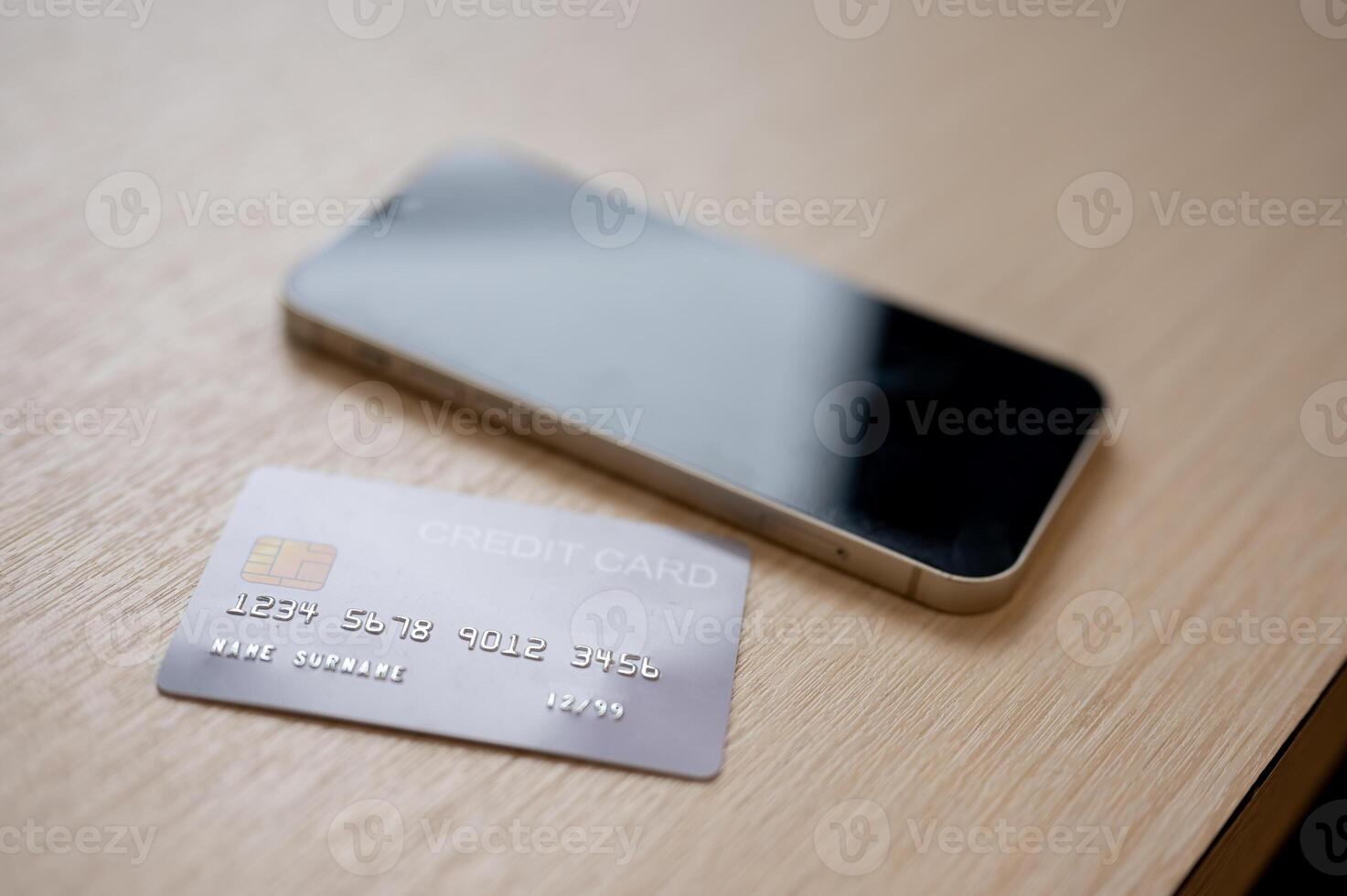 A close-up of a credit card and a smartphone placed on a wooden table indoors. photo