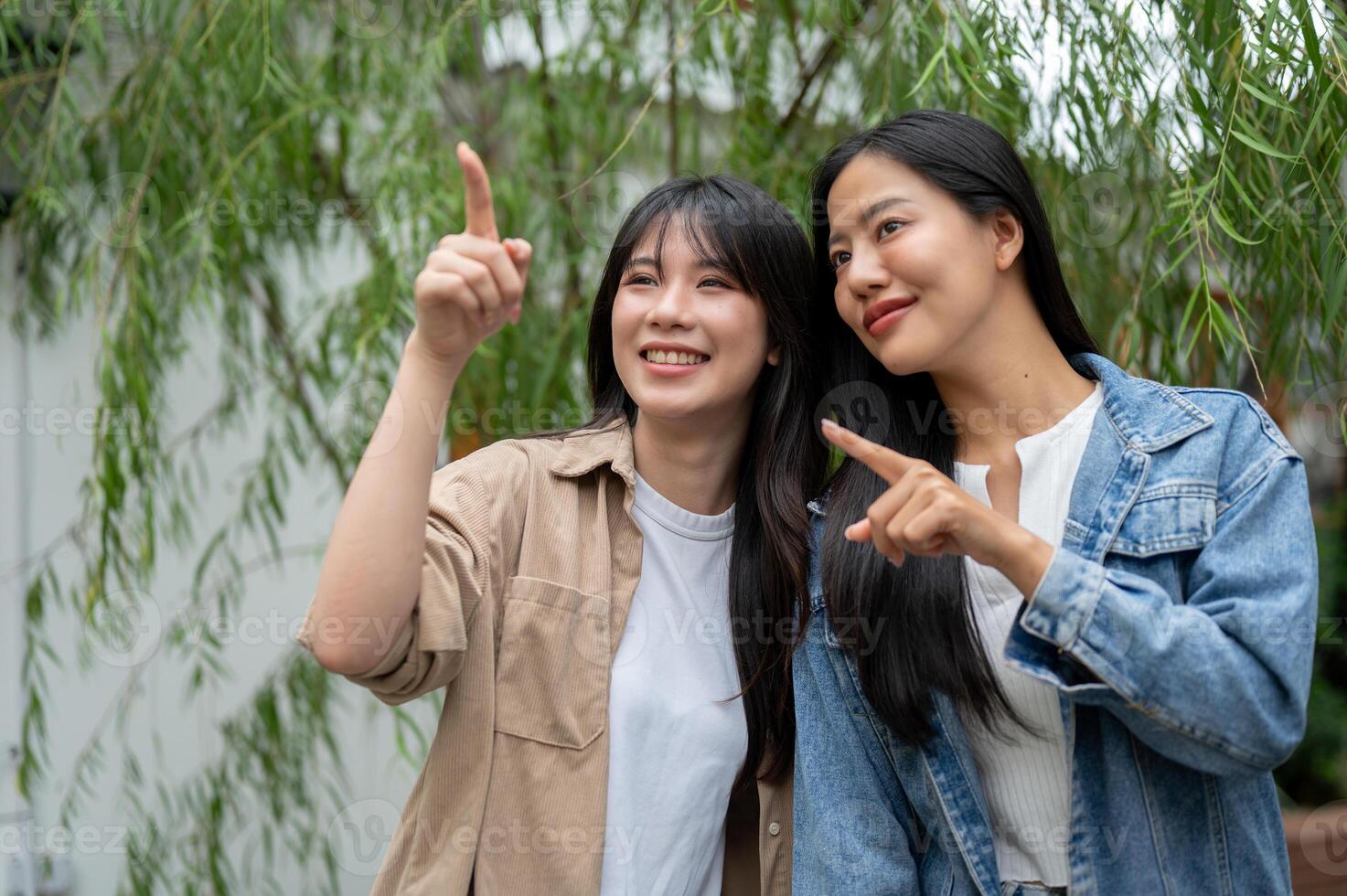 Two attractive Asian female friends are enjoying the view in a lush home garden. photo