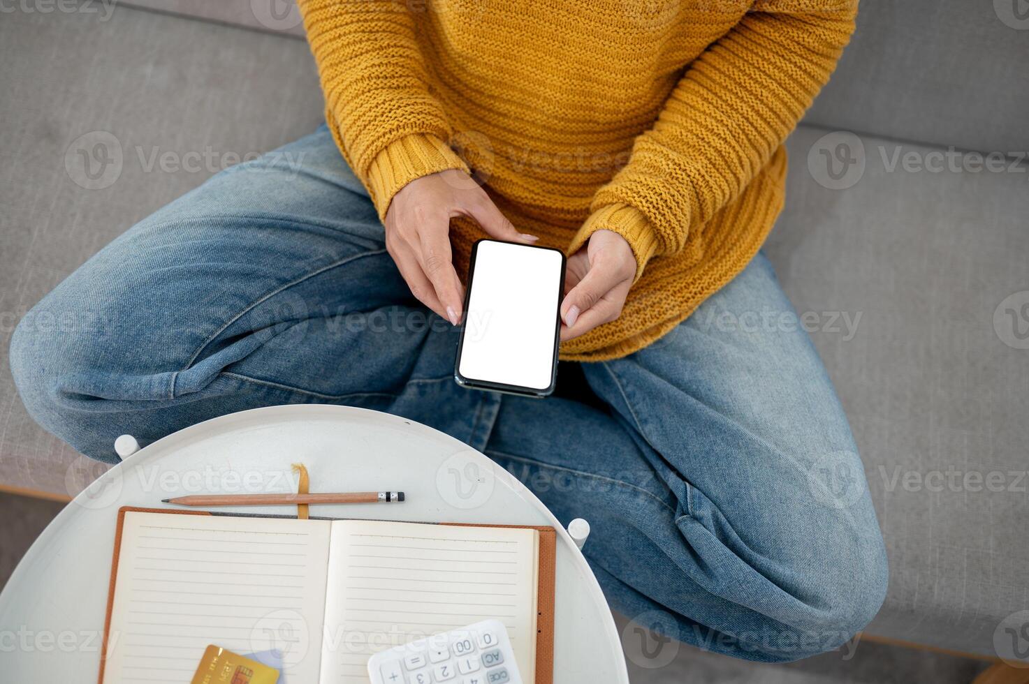 A top view of a woman in casual clothes using her smartphone on a sofa at home. photo