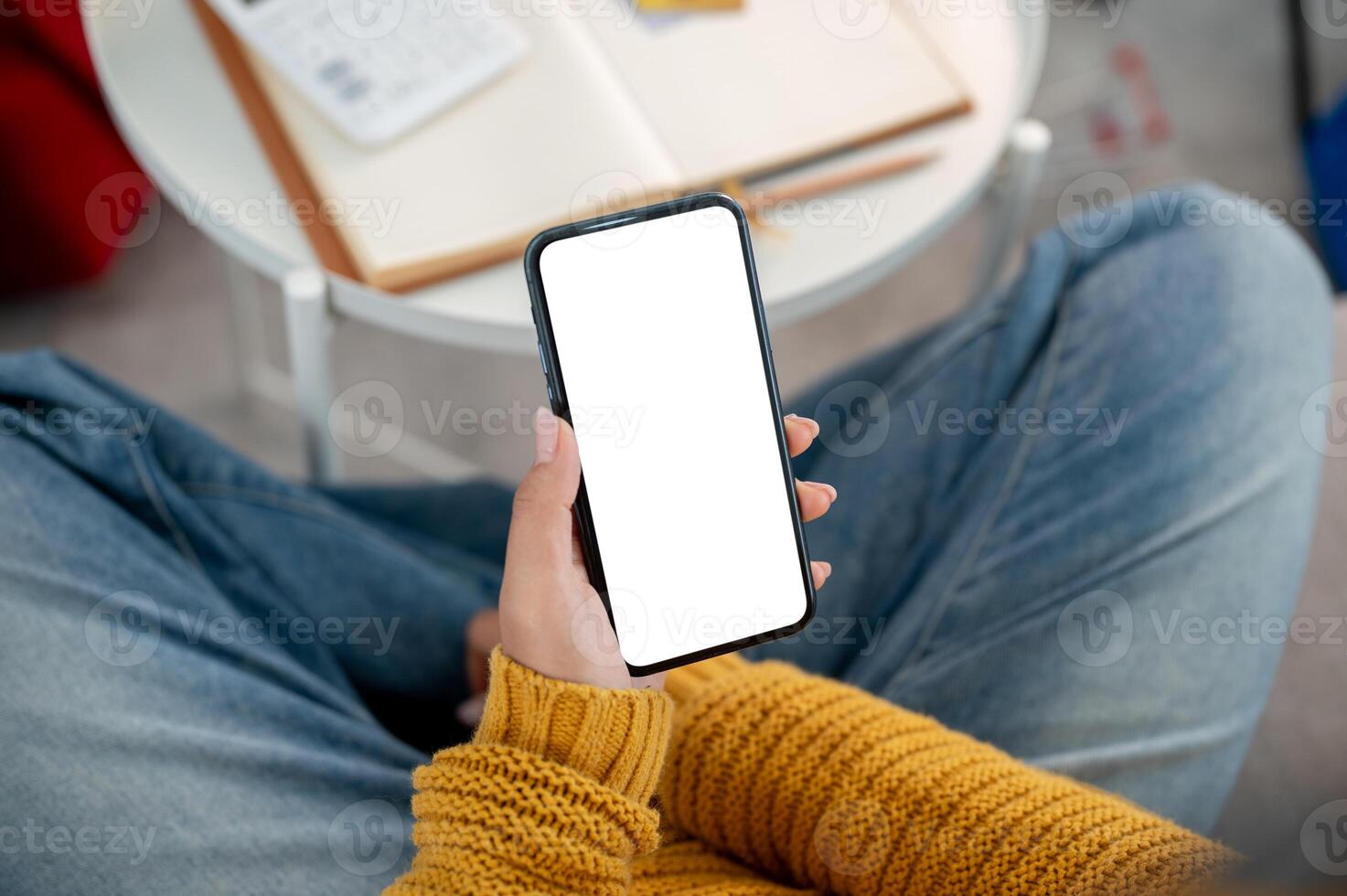 A top view of a woman in casual clothes using her smartphone on a sofa at home. photo