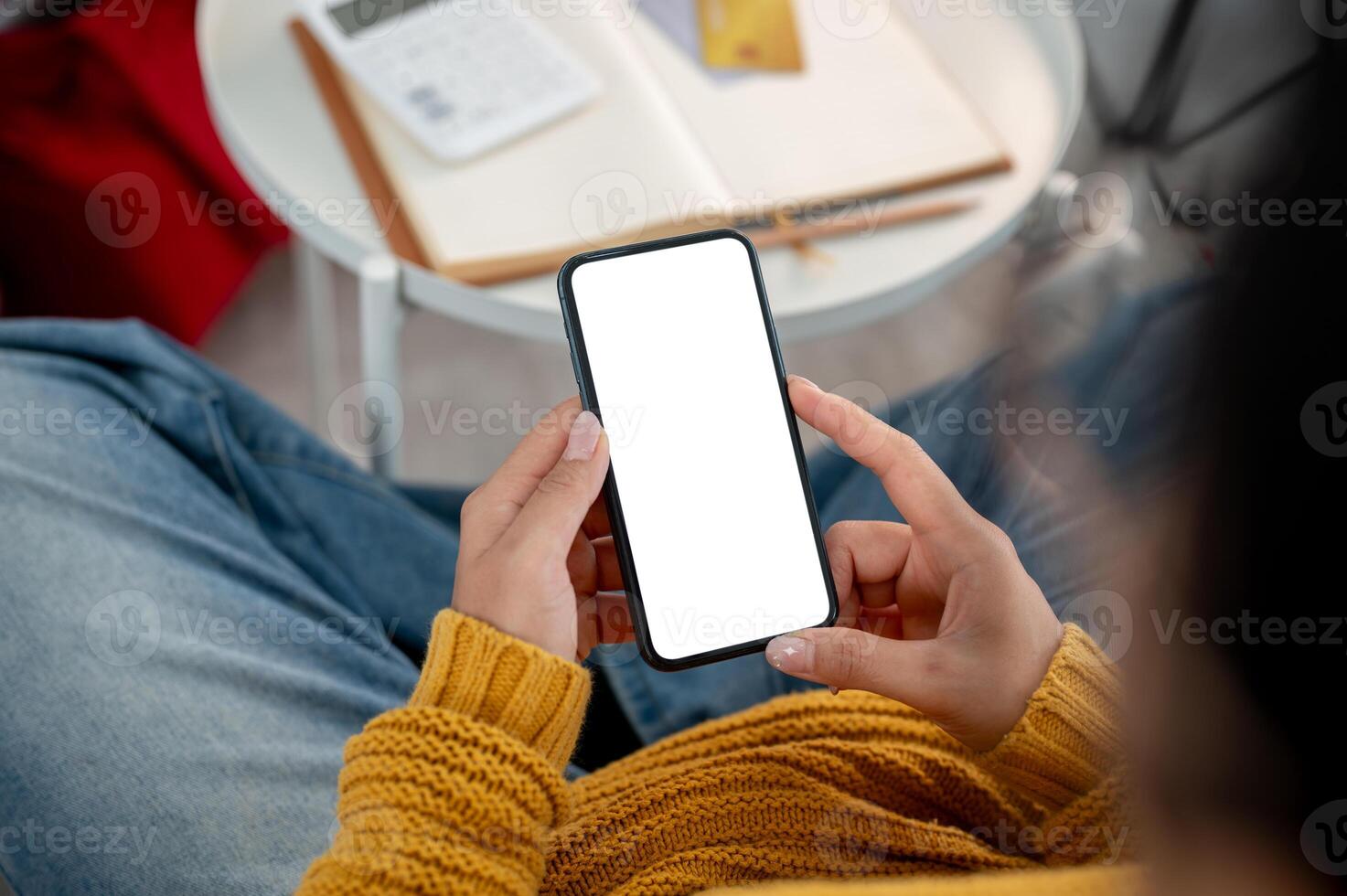 A top view of a woman in casual clothes using her smartphone on a sofa at home. photo