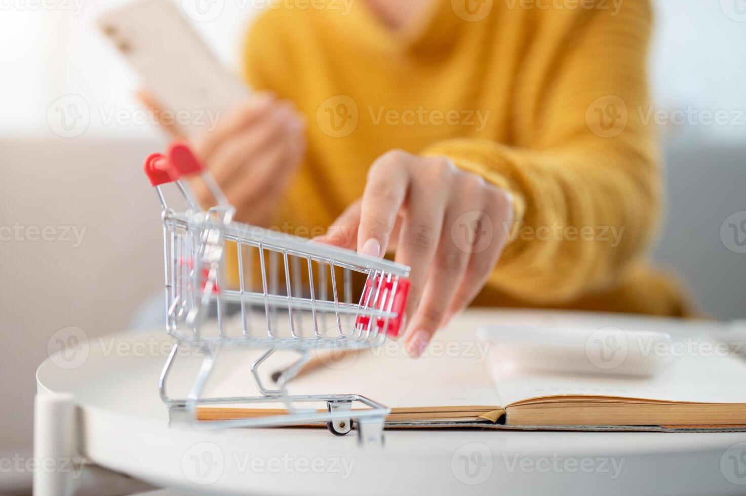 A close-up of a woman touching a mini shopping cart model on a table. shopping online, lifestyles photo