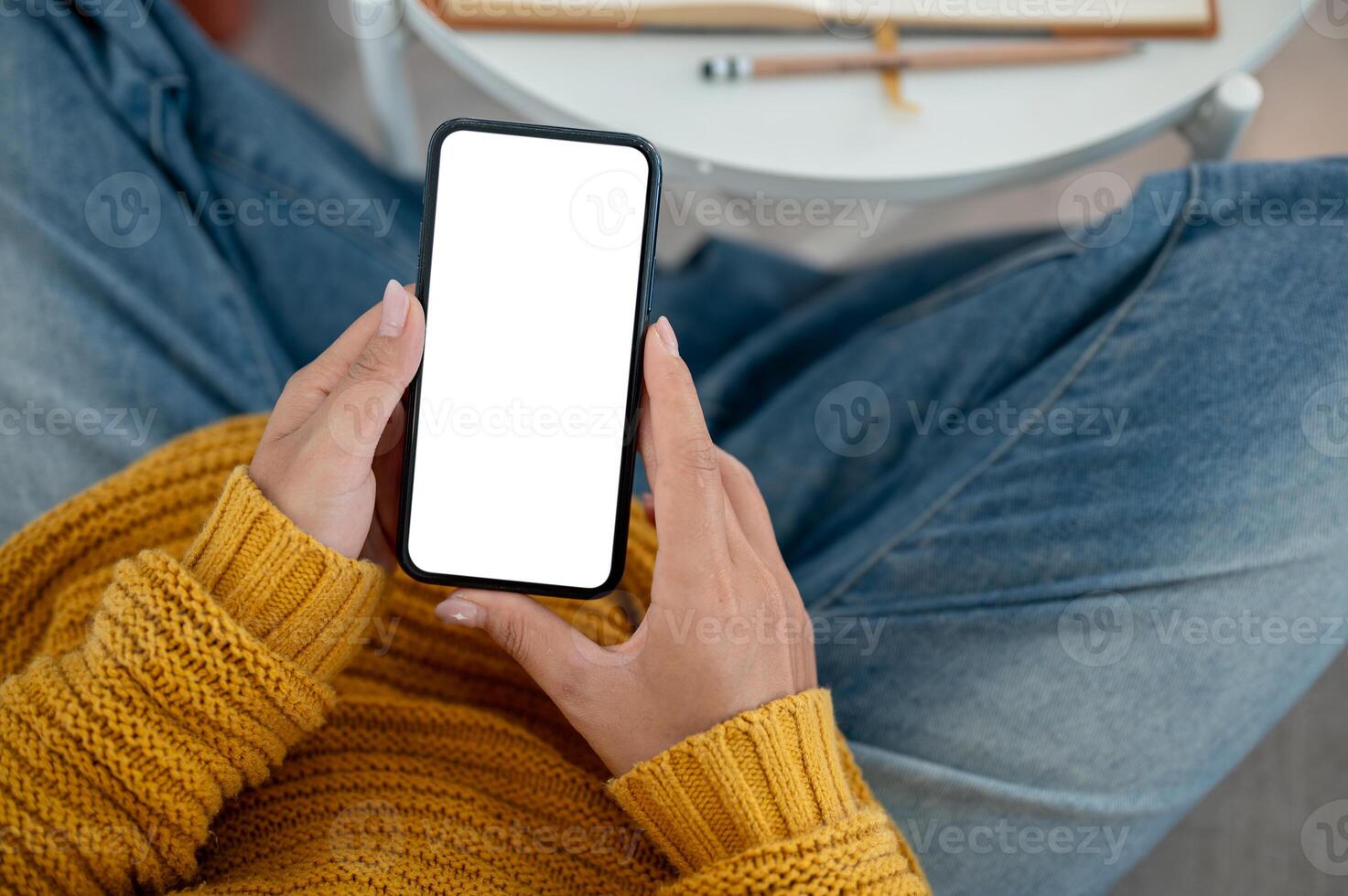 A top view of a woman in casual clothes using her smartphone on a sofa at home. photo