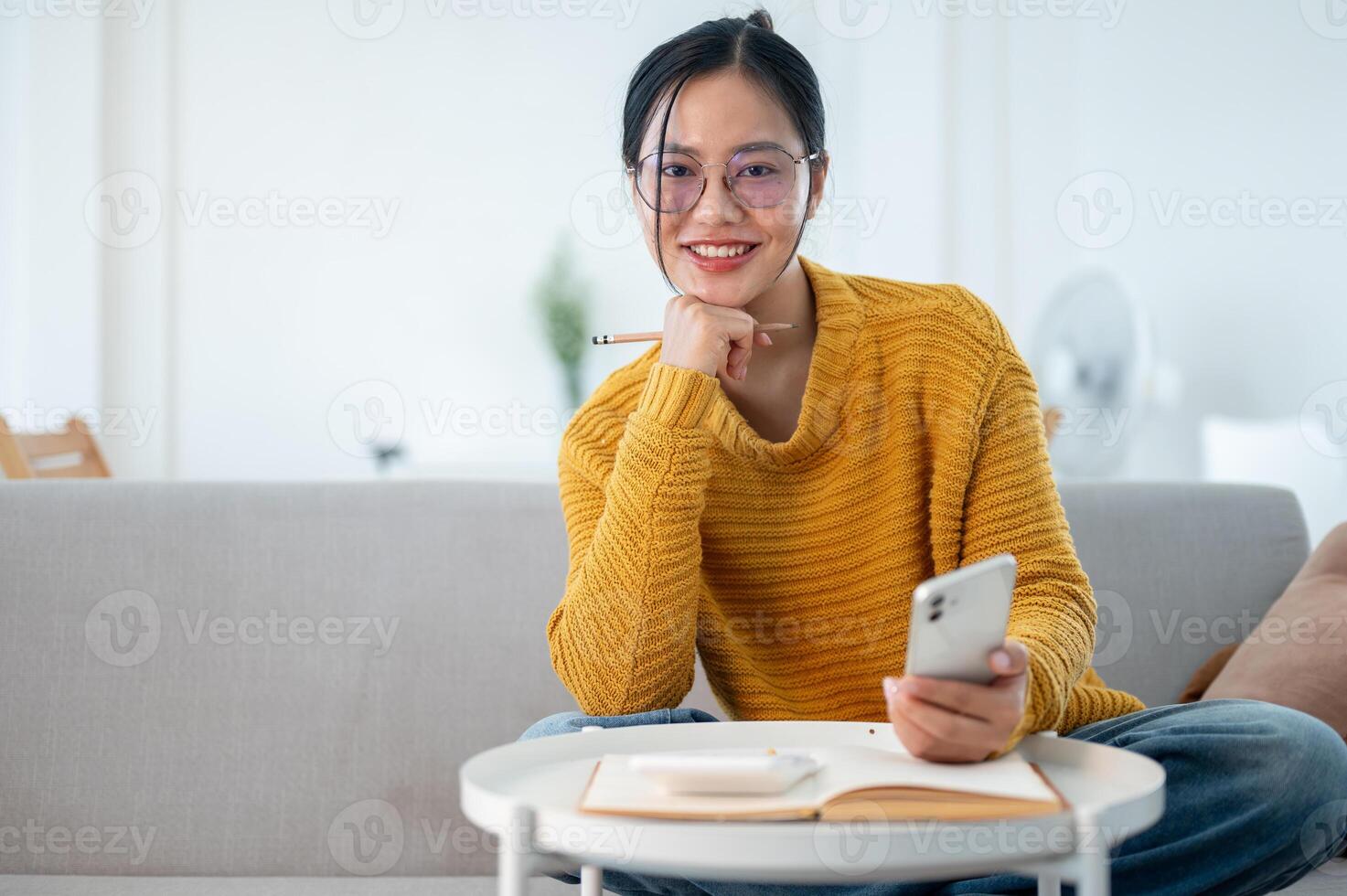 A happy Asian woman planning her household expenses and managing her savings, smiling at the camera. photo