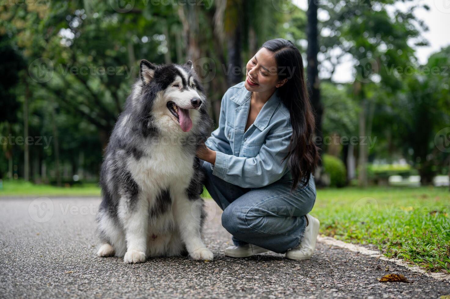 A woman is sitting and talking with her Siberian husky while taking it for a walk in the park. photo