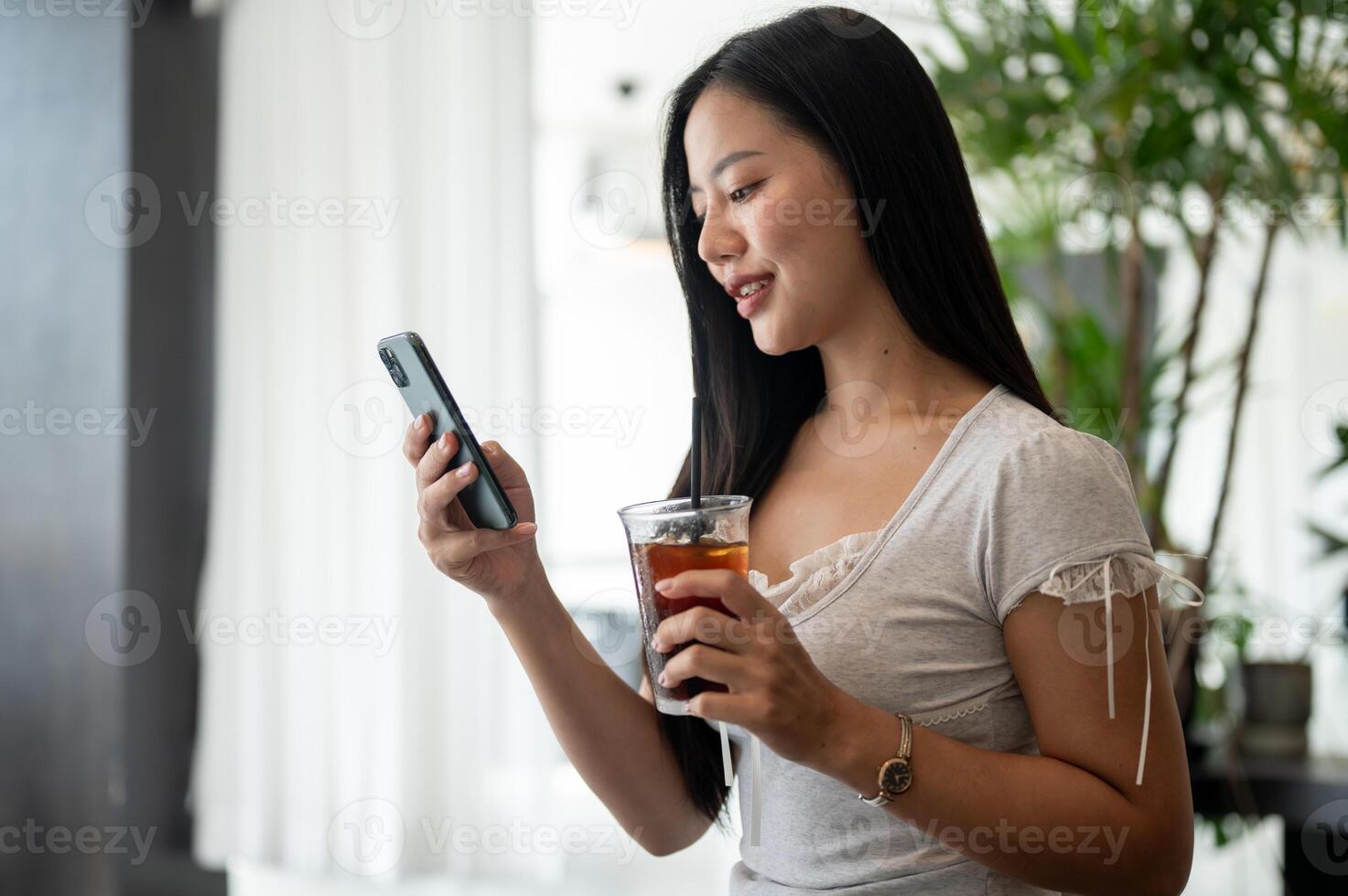 A woman is relaxing in a coffee shop, reading messages on her smartphone while enjoying a coffee. photo