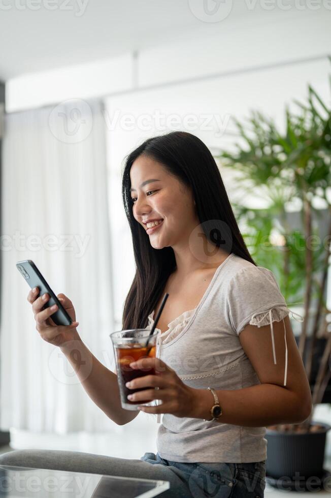 A woman is relaxing in a coffee shop, reading messages on her smartphone while enjoying a coffee. photo