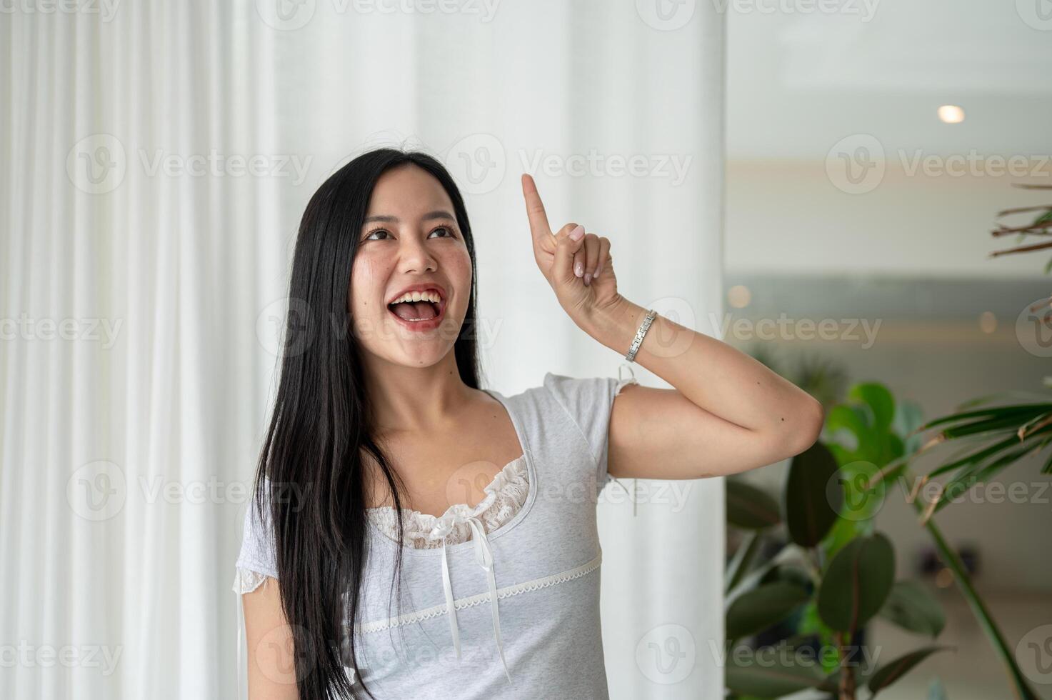 A woman is looking up and pointing her finger in the air, posing as if she just got a brilliant idea photo