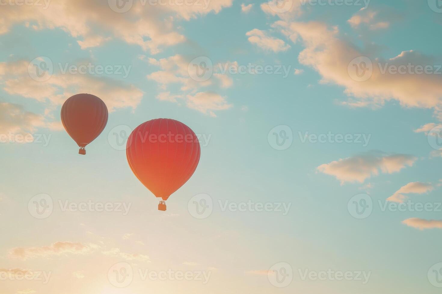 Two vibrant hot air balloons floating under a blue sky filled with fluffy clouds during sunset photo