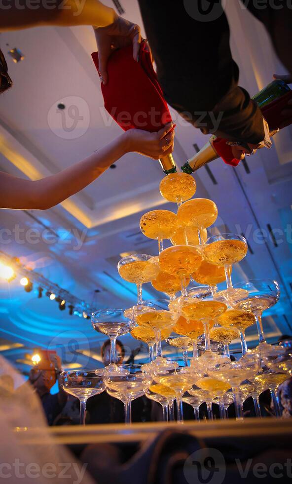 A wedding couple is pouring champagne into a glass photo
