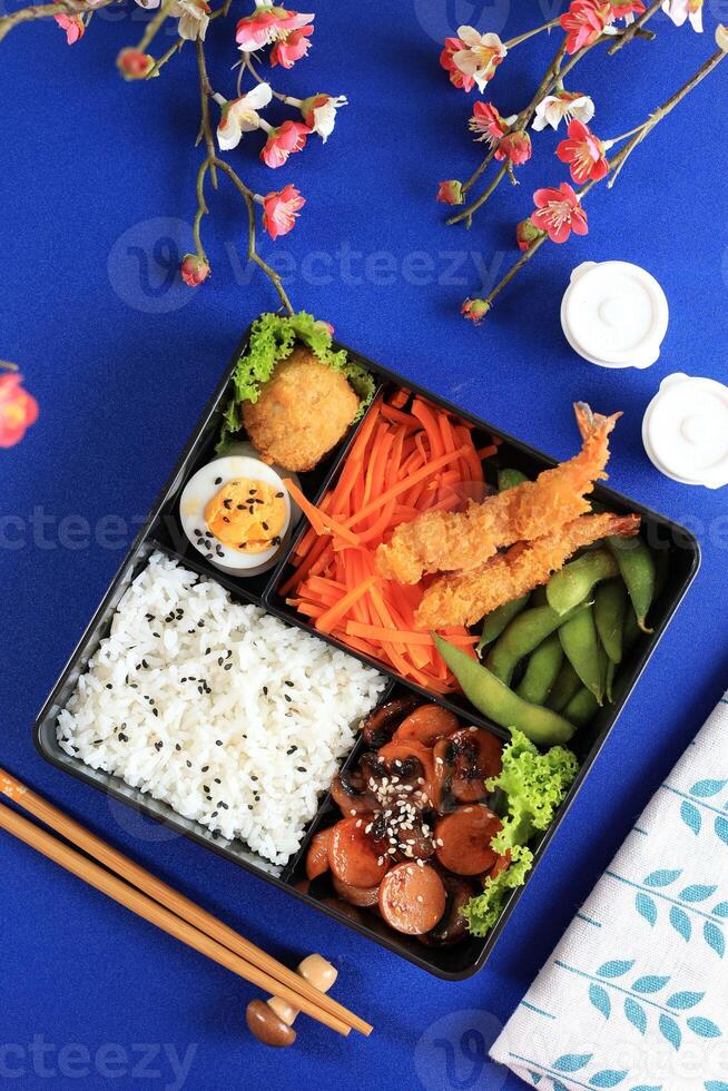 Japanese Bento Lunch Box with Rice, Sausages, Nugget, Edamame, Carrot Salad, and Shrimp Tempura photo