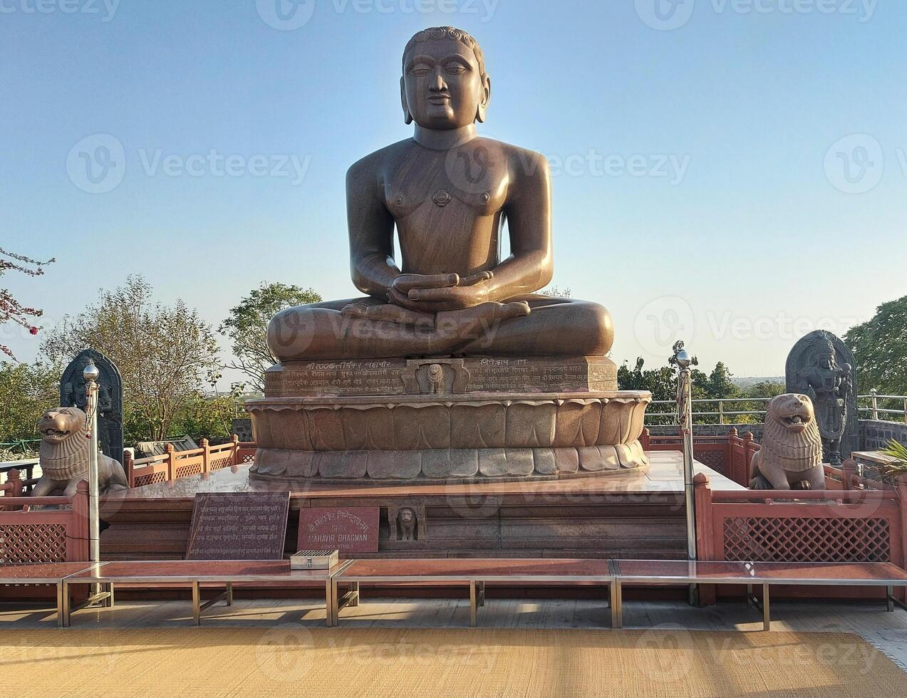A large statue of buddha sitting on a bench photo