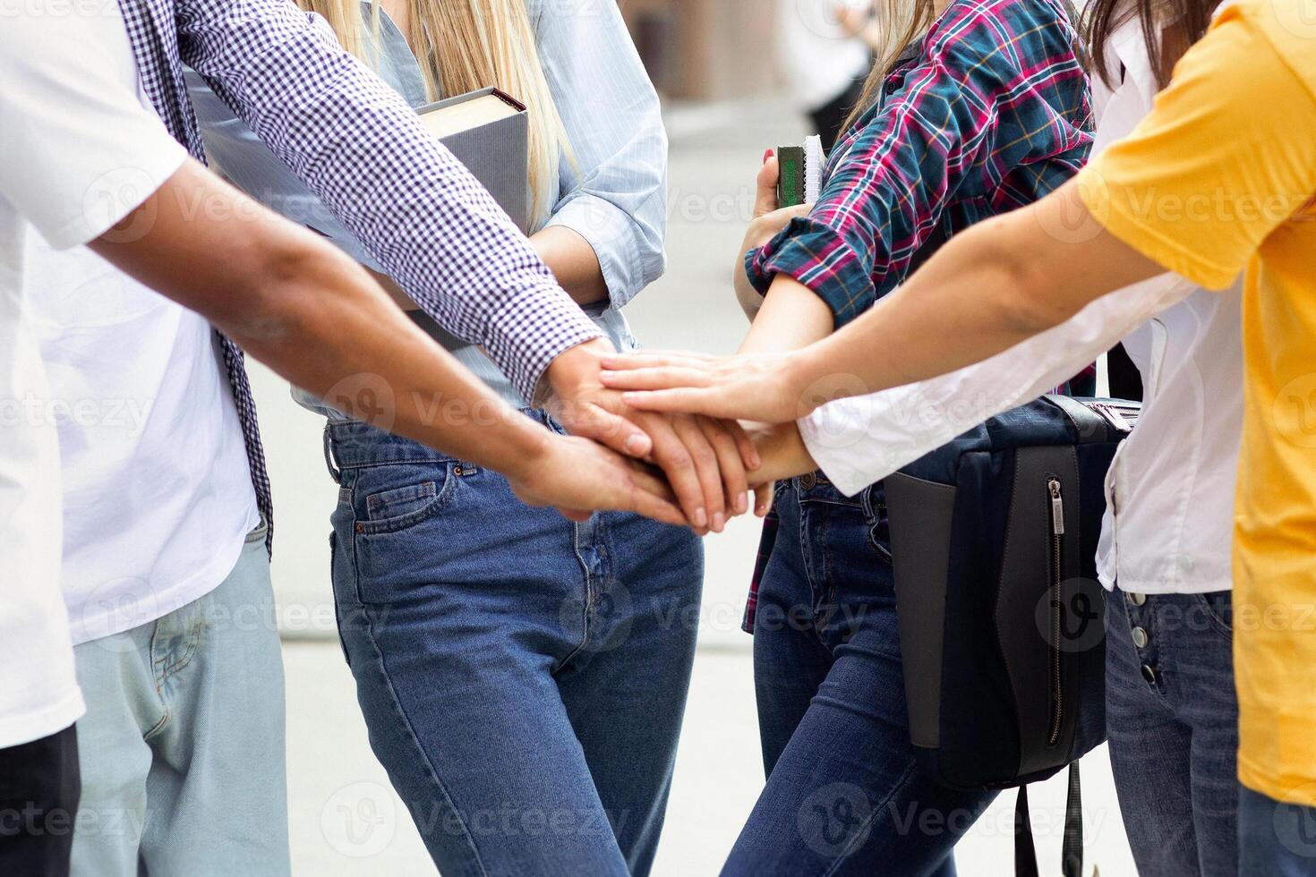 Togetherness, unity concept. Students putting their hands together in college campus photo