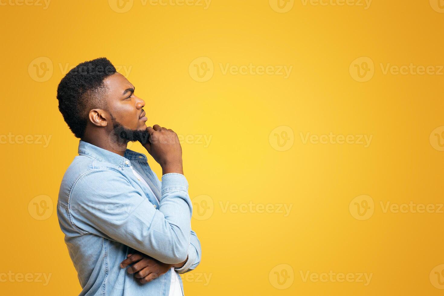 Let me think about it. Profile portrait of thoughtful african american guy on yellow studio background with copy space, panorama photo