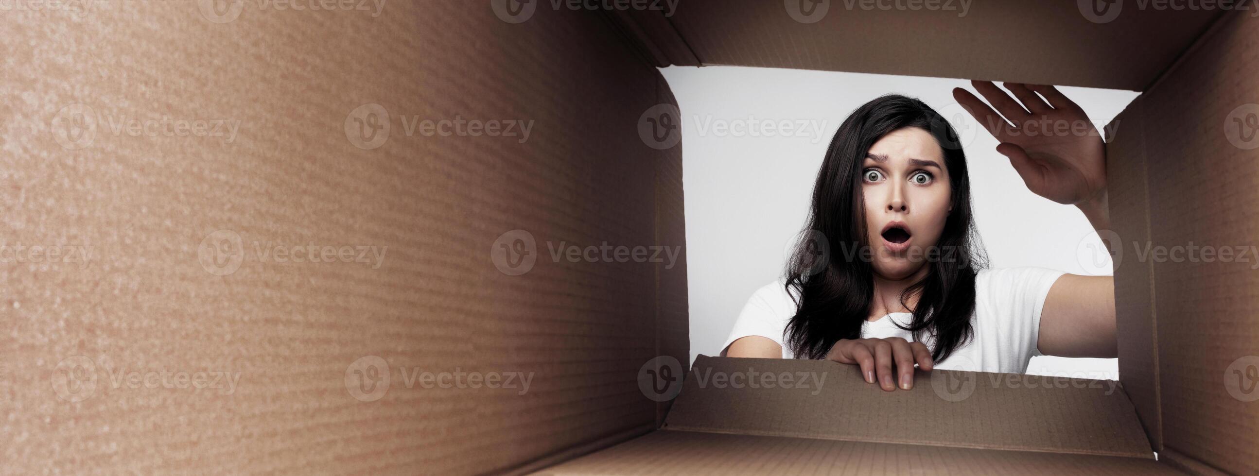 Shocked Young Woman Looking Into Empty Cardboard Moving Box. Transporting Stuff And Changing Apartments Concept photo