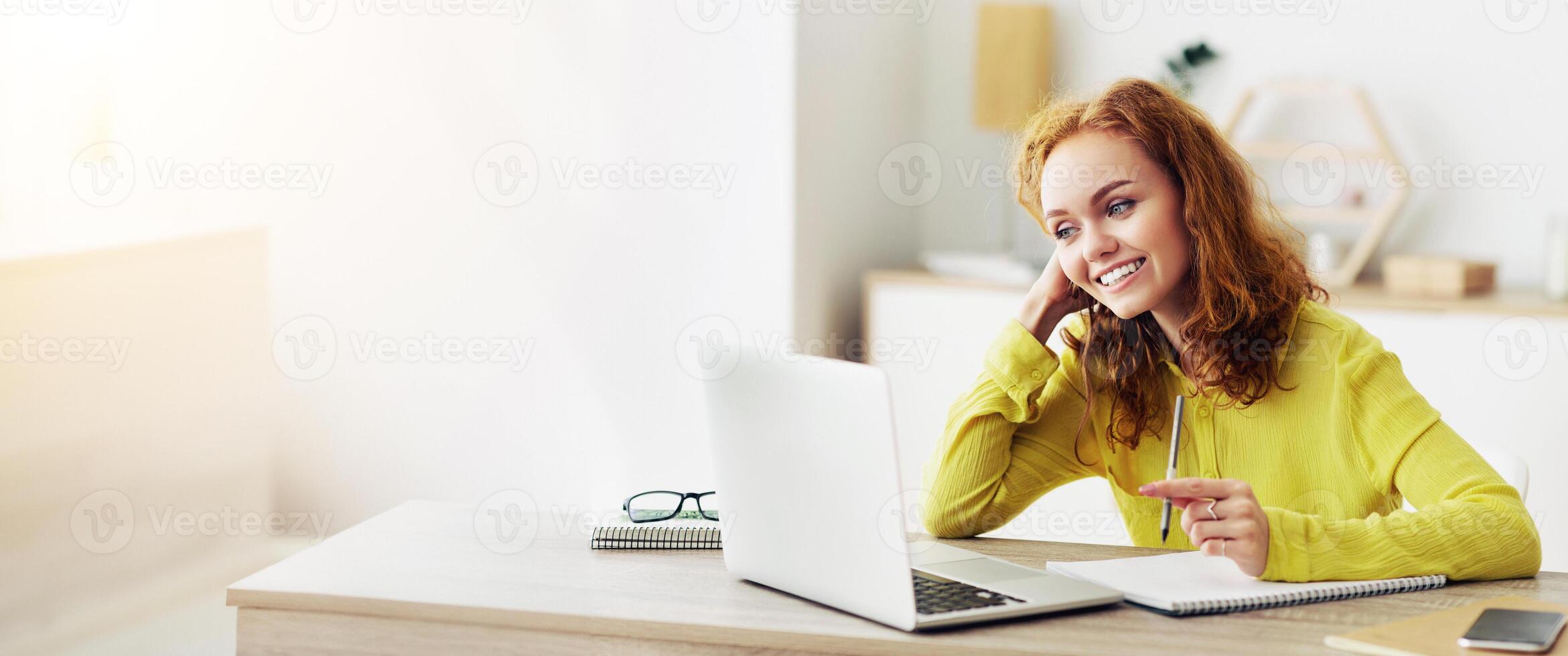 Smiling young female student watching educational lecture online course, writing down notes and summary photo