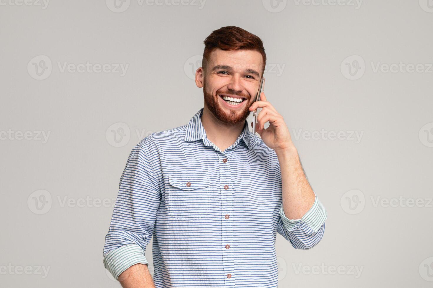 Happy Millennial Guy Talking On Mobile Phone And Smiling, beige background, free space photo