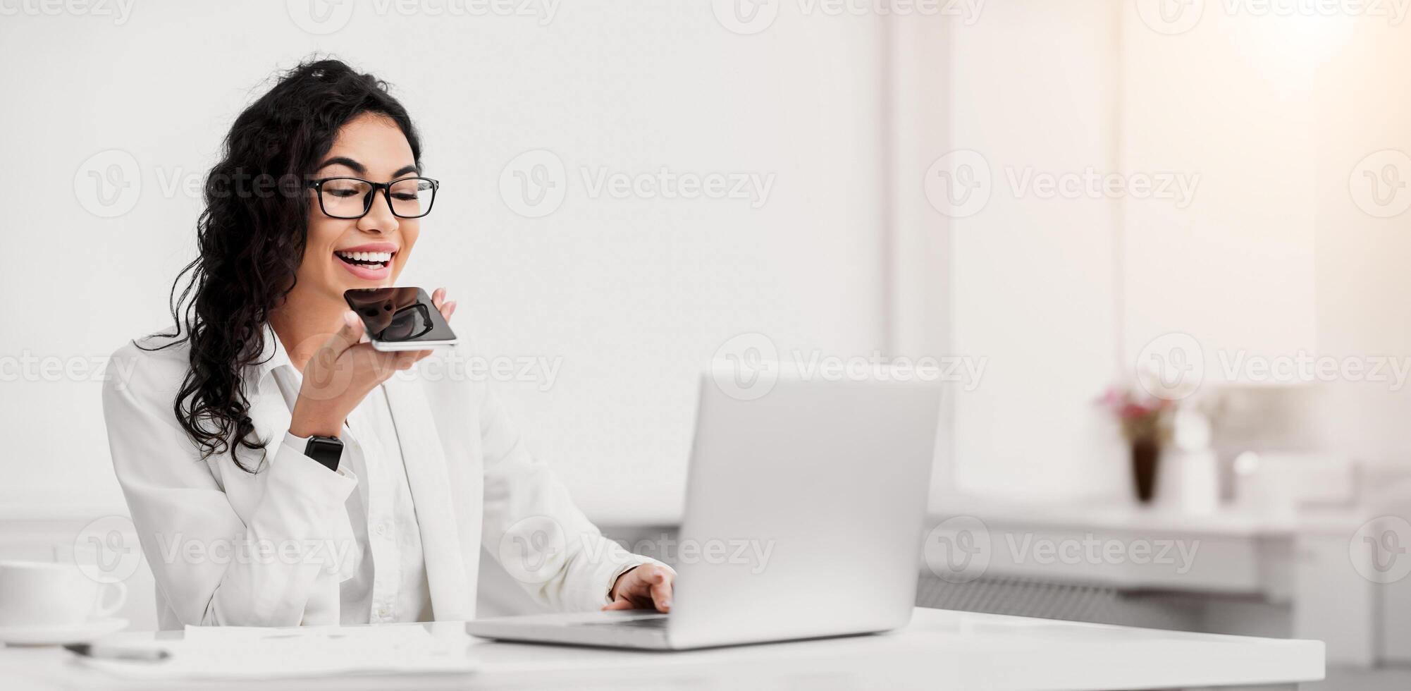 Voice Search. Mexican manager using personal mobile assistant app and working on laptop. Copy space photo
