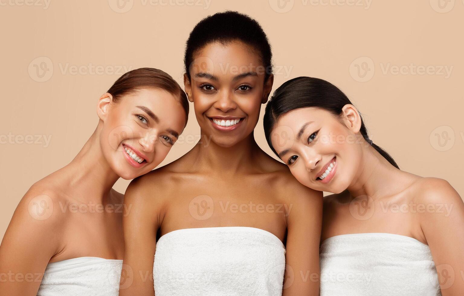 Beauty Of Body. Three Multiracial Women Wrapped In Towels Posing Smiling To Camera Standing On Gray Background photo