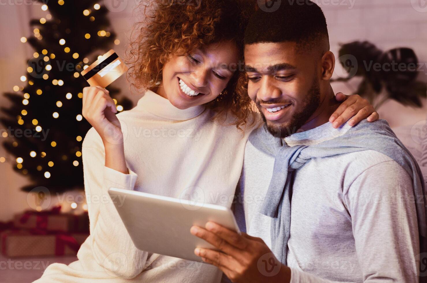Christmas holiday. African-american couple choosing gifts on tablet, using credit card photo