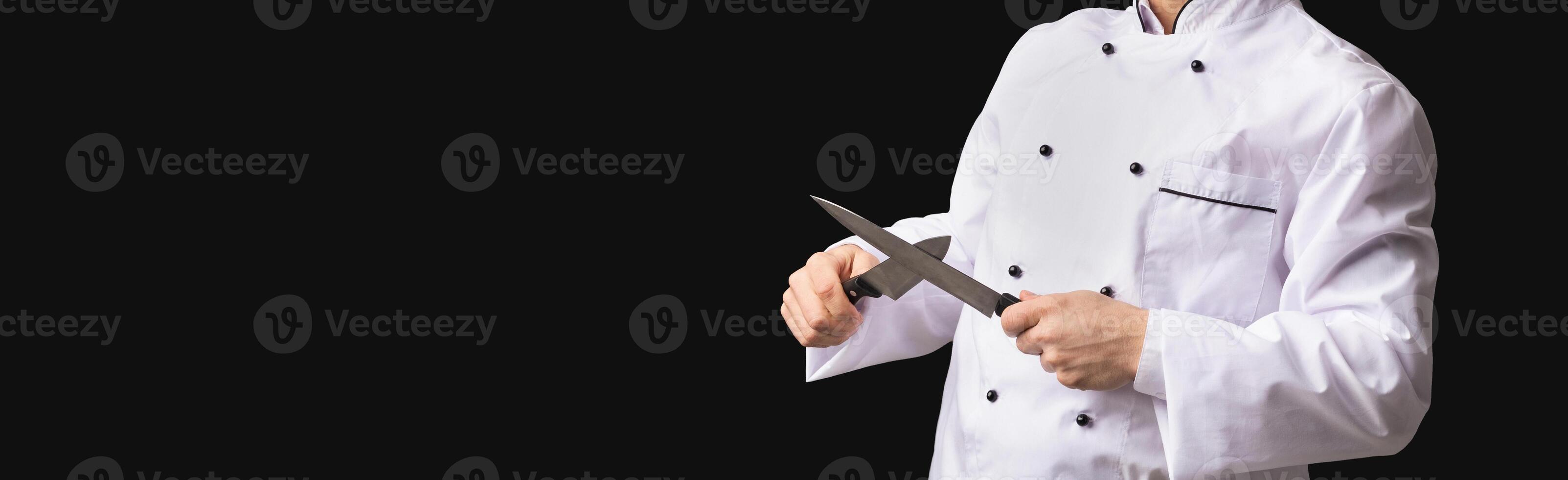 Professional Chef. Funny Cook Guy Sharpening Knives Posing In Studio Over Black Background. Panorama, Free Space For Text photo
