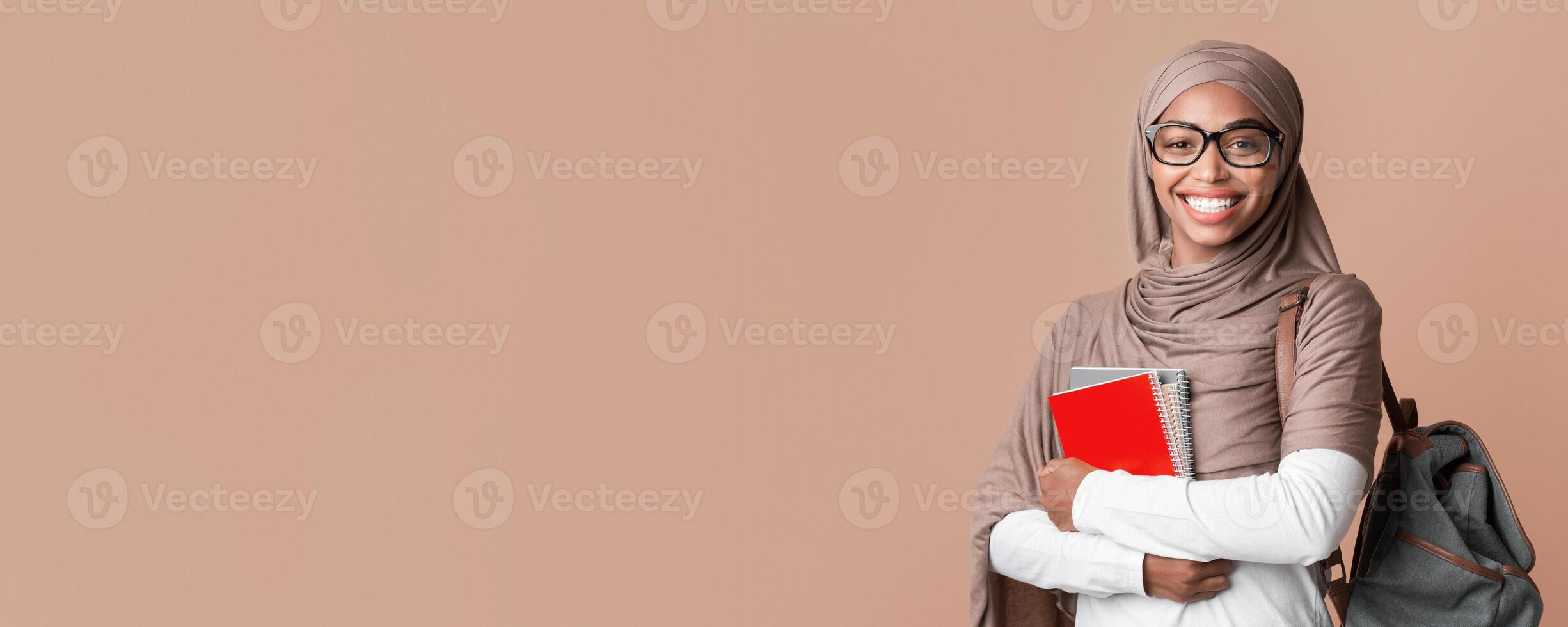 Education Concept. Portrait Of Smiling Black Muslim Girl In Hijab With Backpack And Notepads Posing Over Yellow Background With Empty Space photo