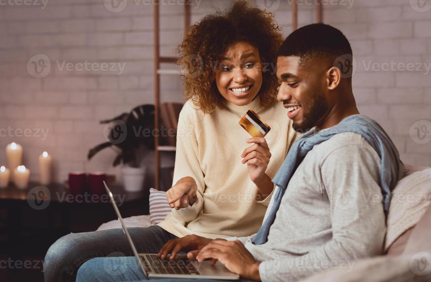 Online banking. Woman asking man doing internet shopping, holding credit card and pointing on laptop photo