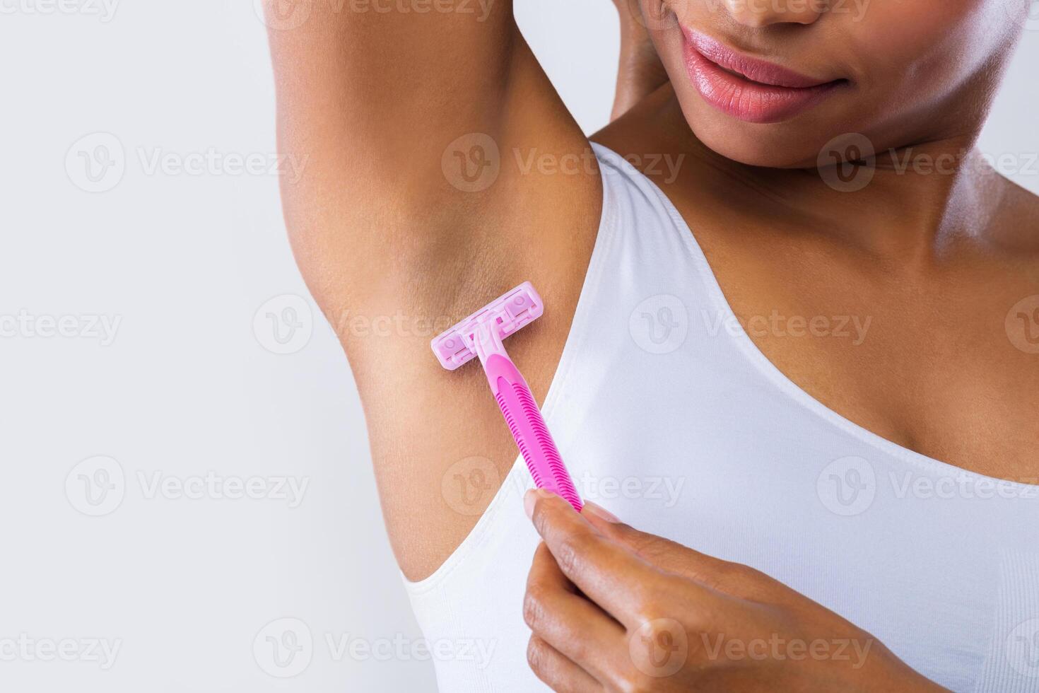 Cropped of black model shaving her armpit over grey background photo