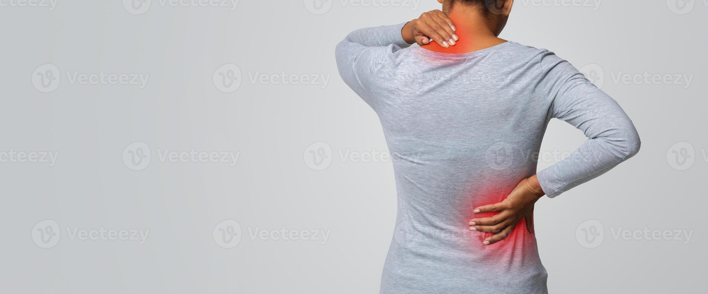 Back view of african woman rubbing her inflamed neck and loins, grey background photo
