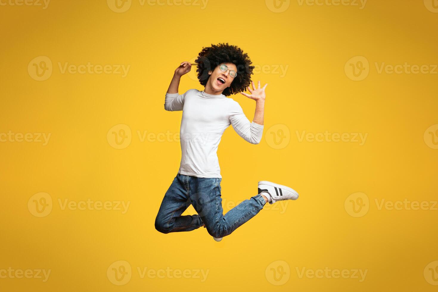 Oh my gush. Ecstatic and amazed black guy jumping on orange background, playing like a girl photo