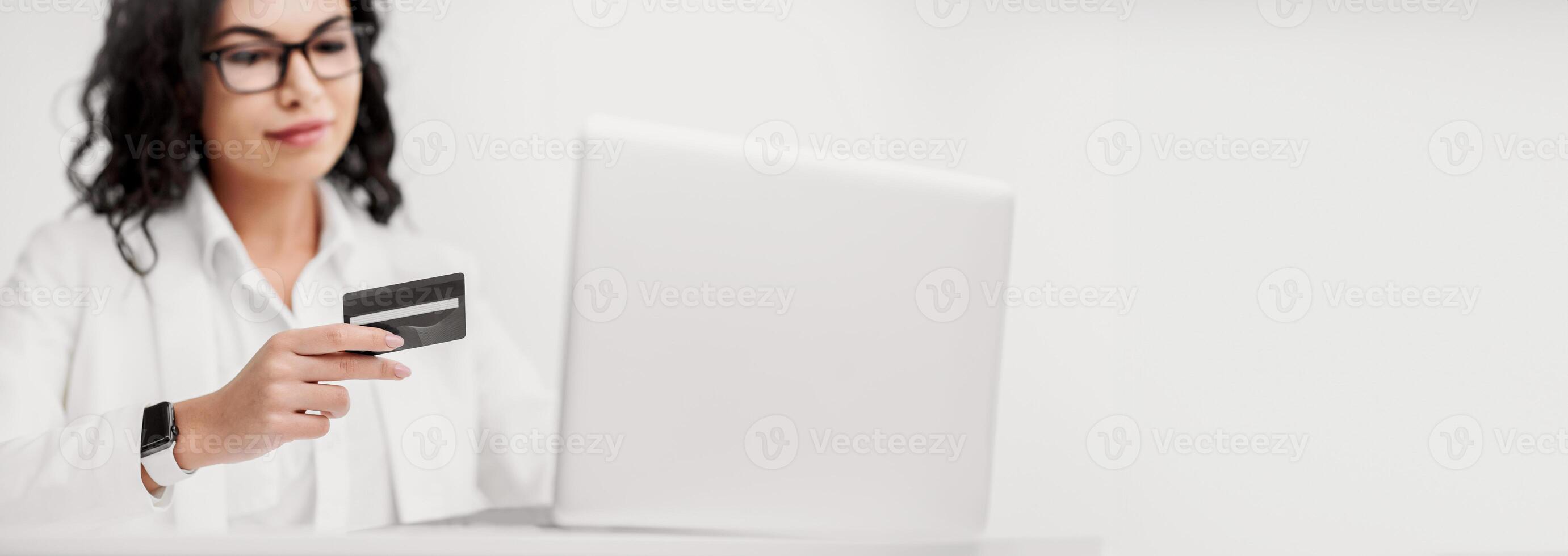 Credit Card Security. Mexican businesswoman holding credit card and entering security code using laptop photo