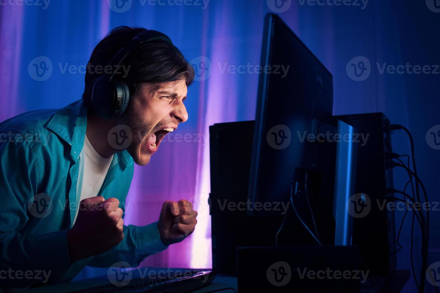 Professional Gamer Young Man Playing and Winning in Shooter Online Game. Room Lit by Neon Lights photo