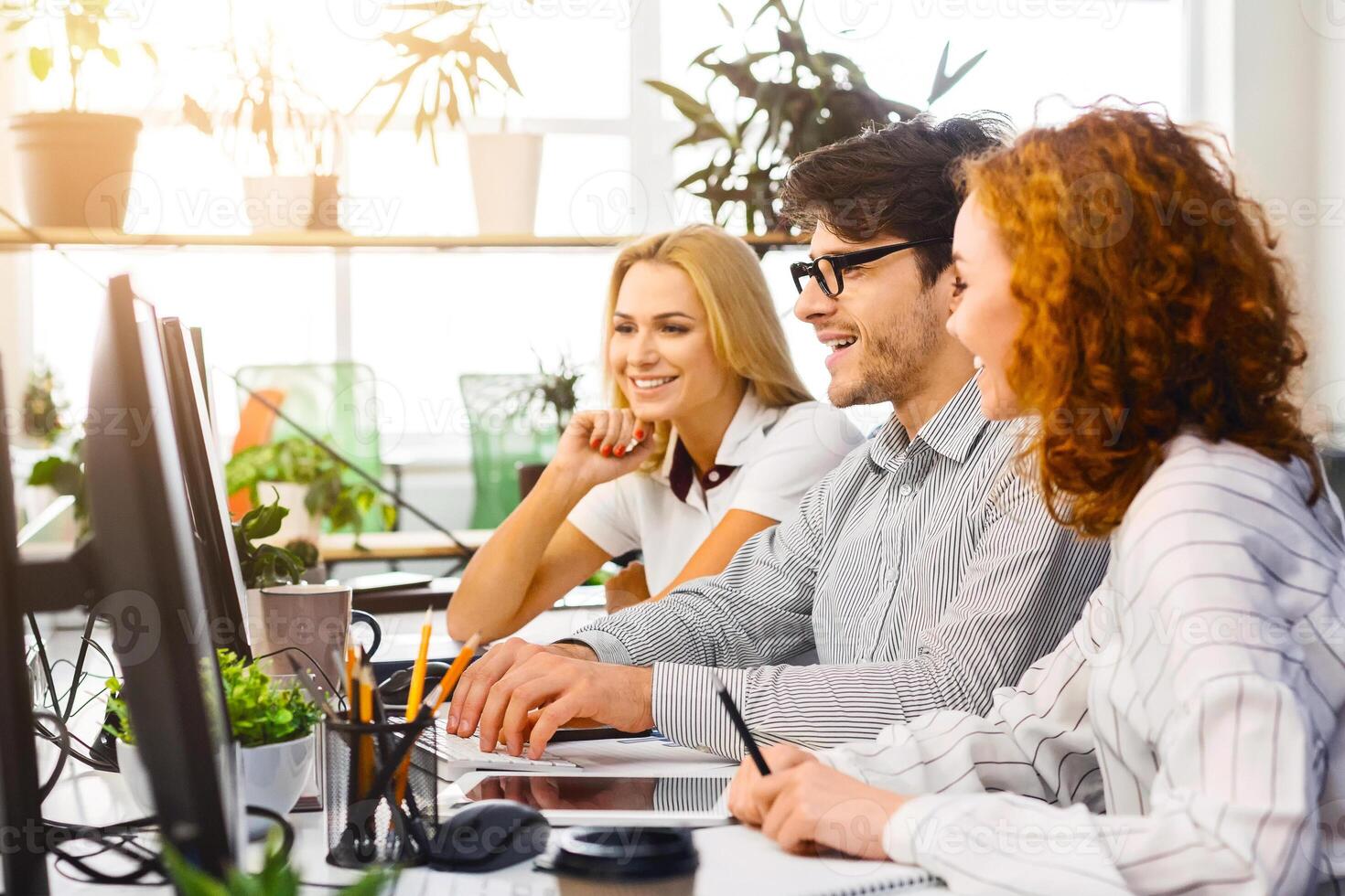 Collaborative Team on Laptops at Trendy Workspace. Energetic team focusing on laptops at a sleek workspace, sharing ideas while creating a positive and productive vibe. photo