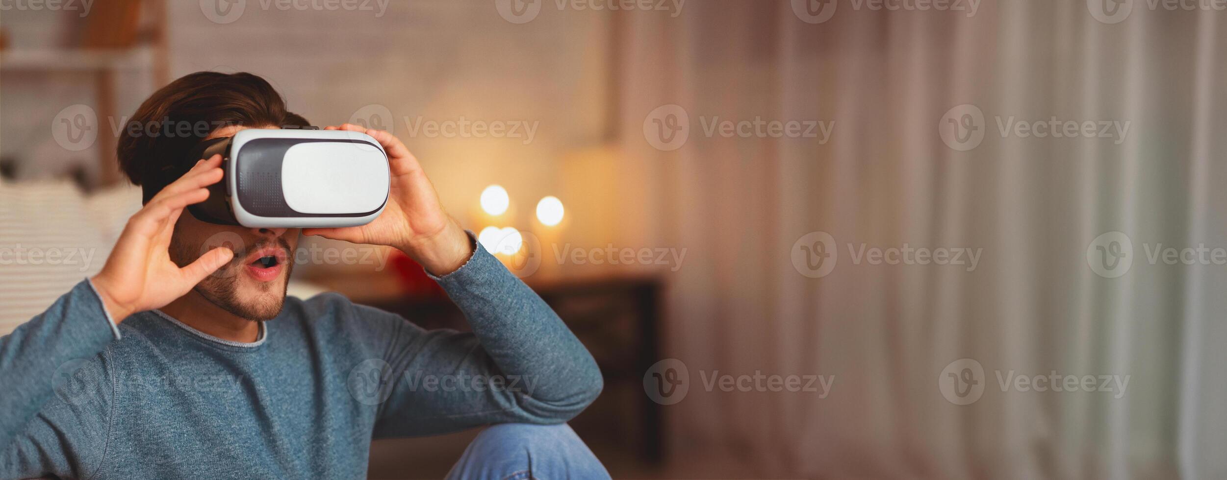 Virtual Reality. Young Man Using VR Headset Playing Videogame Indoor In The Evening. Selective Focus photo