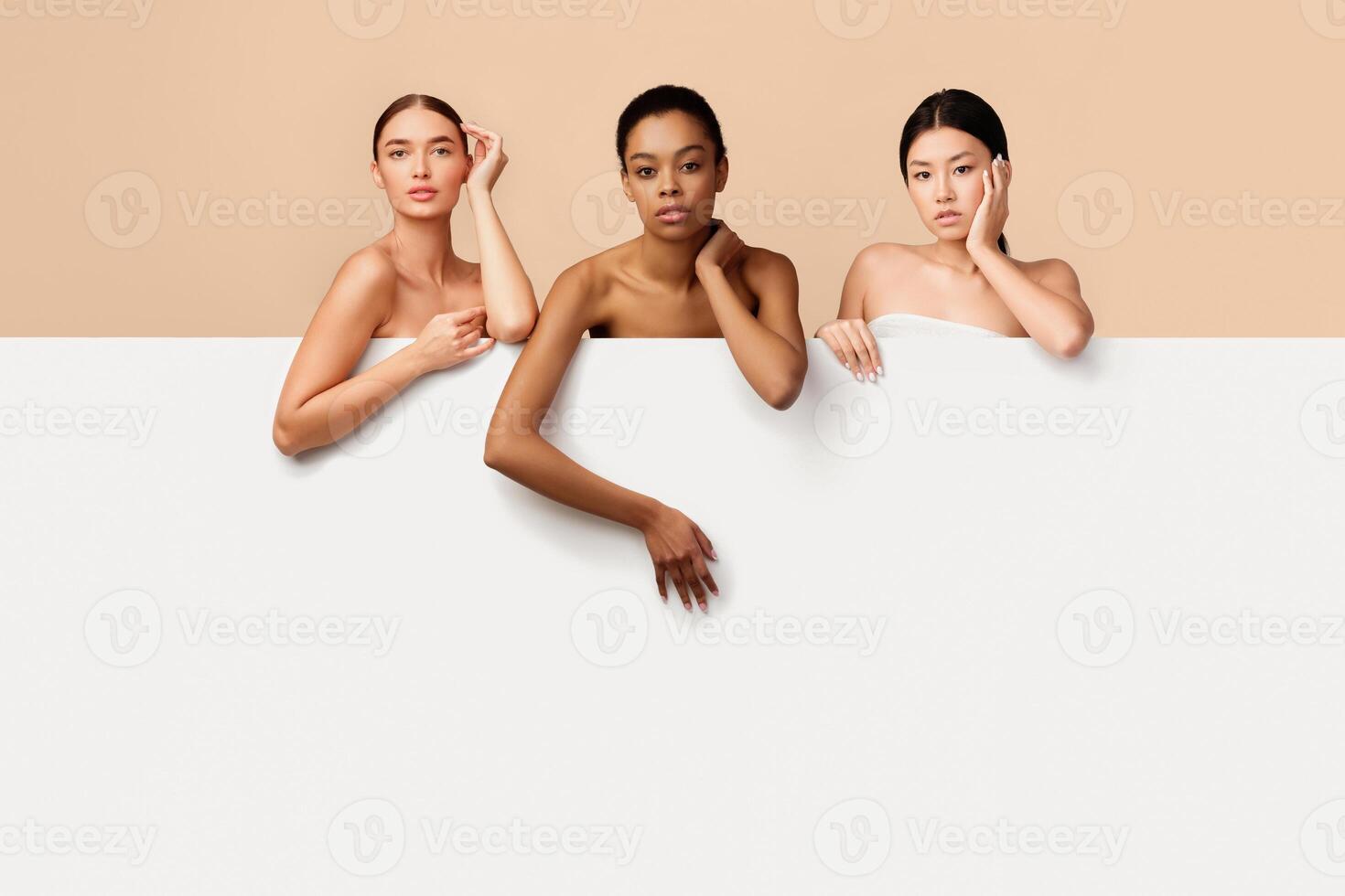 Multiracial Beauty. Three Mixed Women Posing Standing Behind White Board For Text Posing Over Gray Studio Background. Copy Space photo