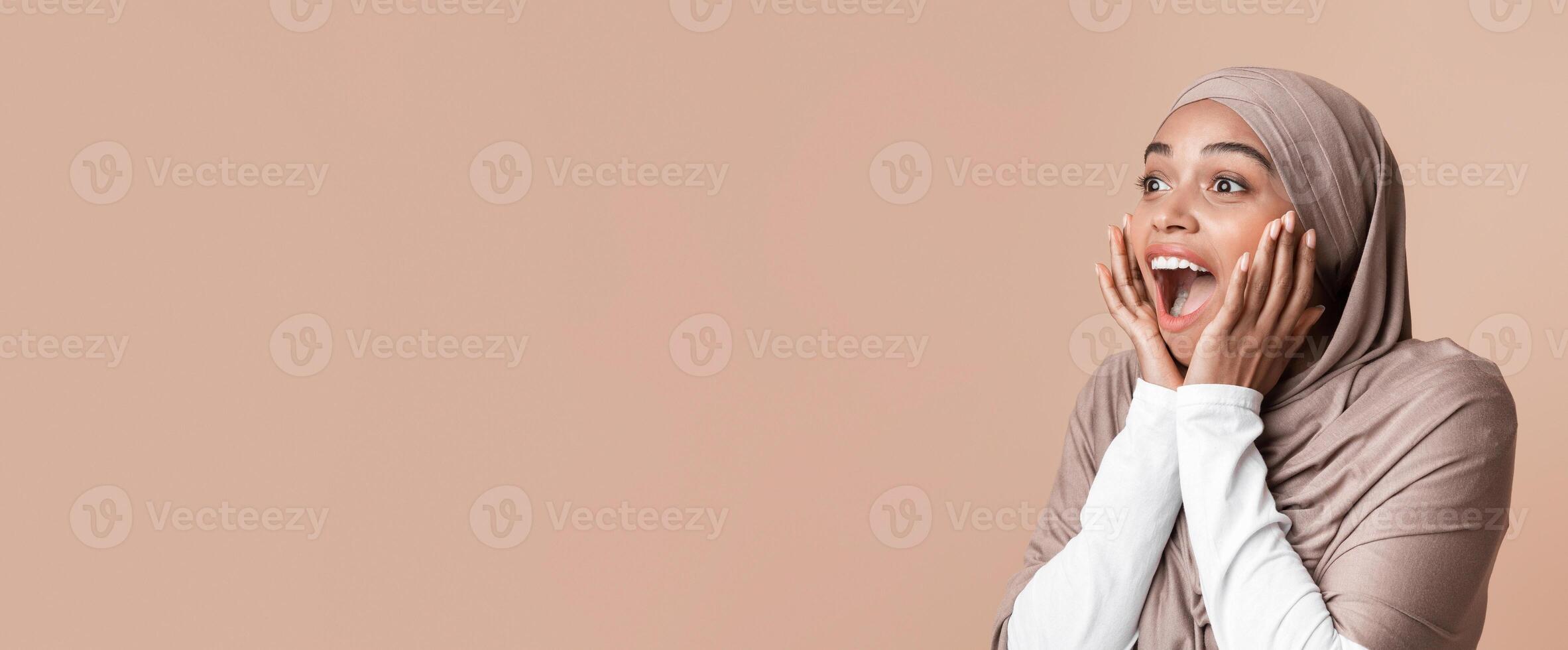 Amazing Offer. Portrait of black muslim girl in hijab looking at copy space and exclaiming in amazement, standing over yellow background, free space photo