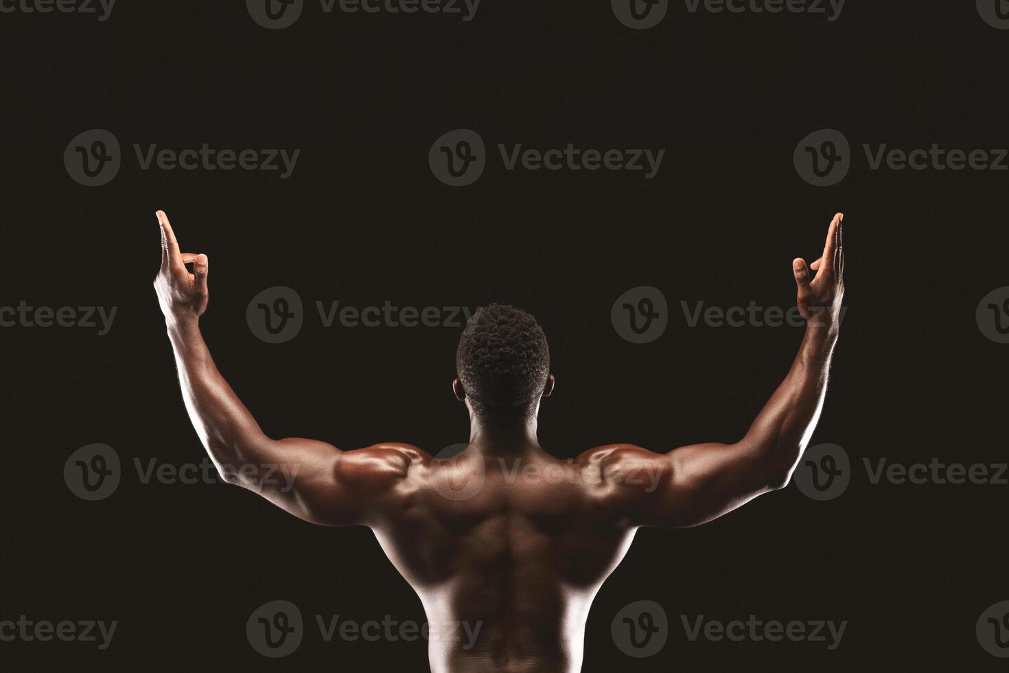 A muscular man with raised arms, back view, in a celebratory pose, against a black background. photo