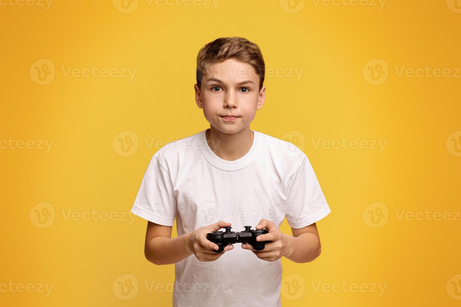Concentrated boy playing game with joystick on orange studio background photo