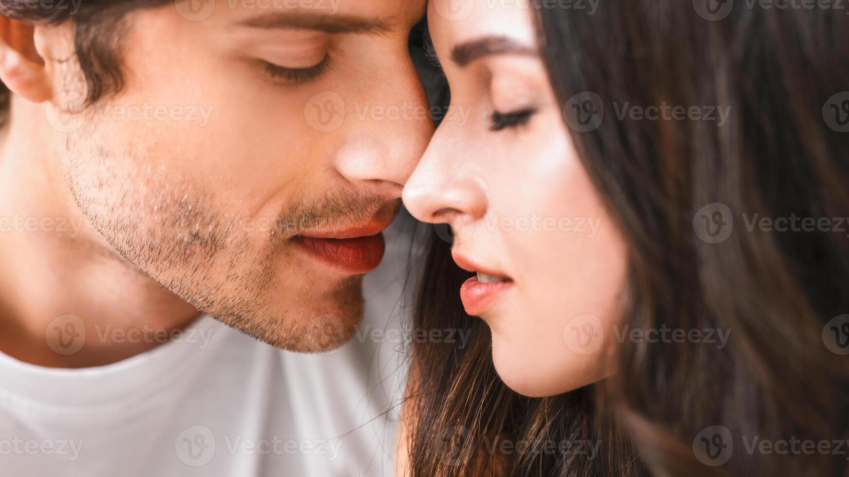 A close-up shot of a young man and woman about to kiss. They are looking at each other with love and affection, their noses touching, their eyes closed photo