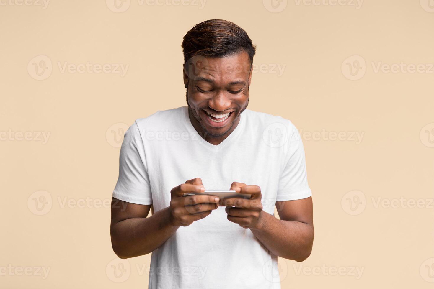 Mobile Gaming. Excited Black Man Using Cellphone Playing Online Games Standing Over Yellow Background. Studio Shot photo