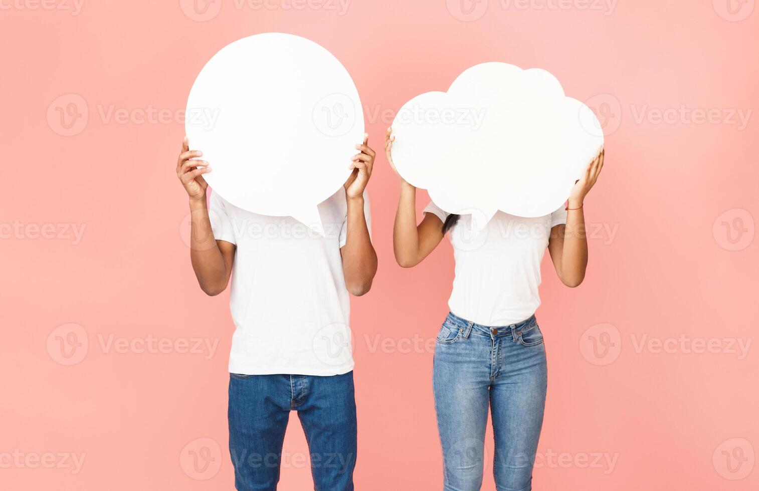 Speech bubbles. Couple holding empty boards, closing their faces over pink background photo